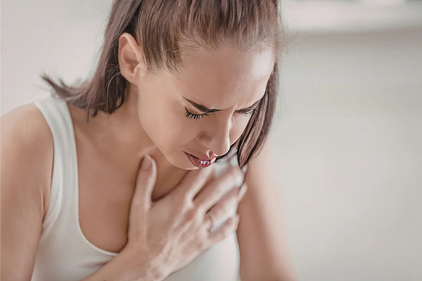 Pregnant woman experiencing heartburn with a glass of water on the table