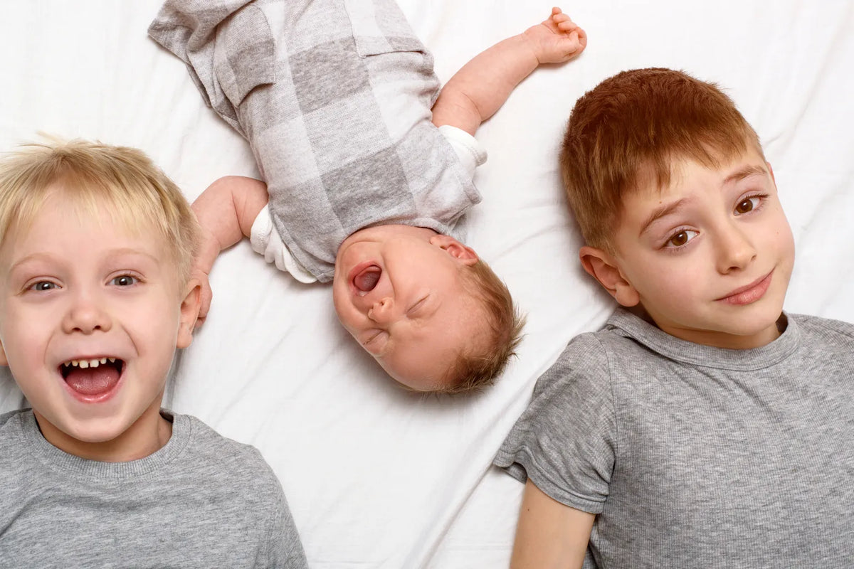 Older child gently touching newborn baby during family bonding moment at home